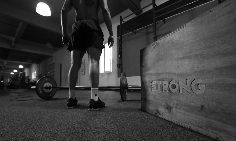 man standing next to barbell strong