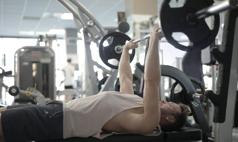 man doing bench press in gym
