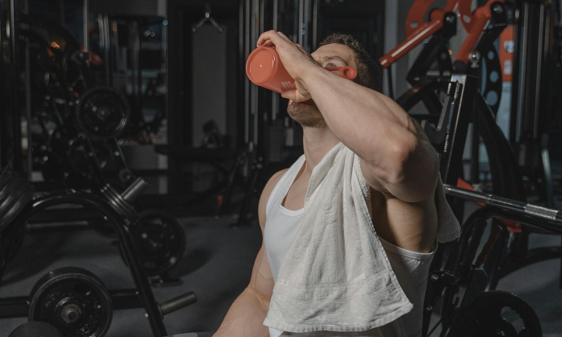 man sitting in gym drinking protein shake