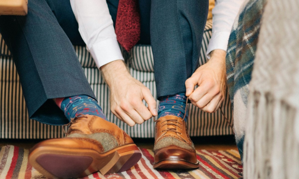 man tying brown lace up shoes