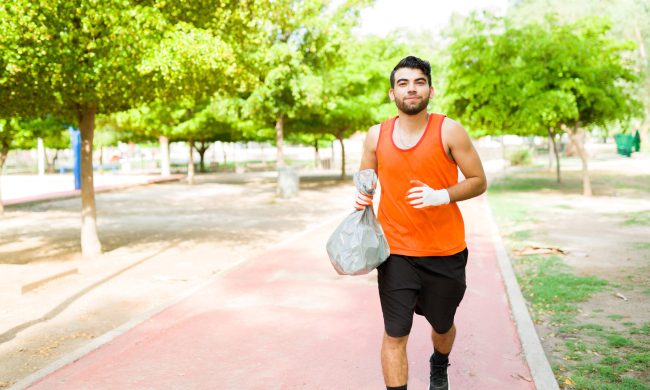 man plogging outside jogging running carrying trash bag