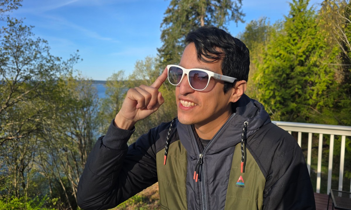A man wearing solos glasses and pressing the side button to activate them
