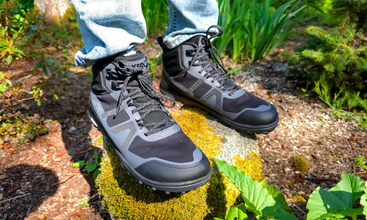 A man wearing Xero shoes while standing on a mossy rock