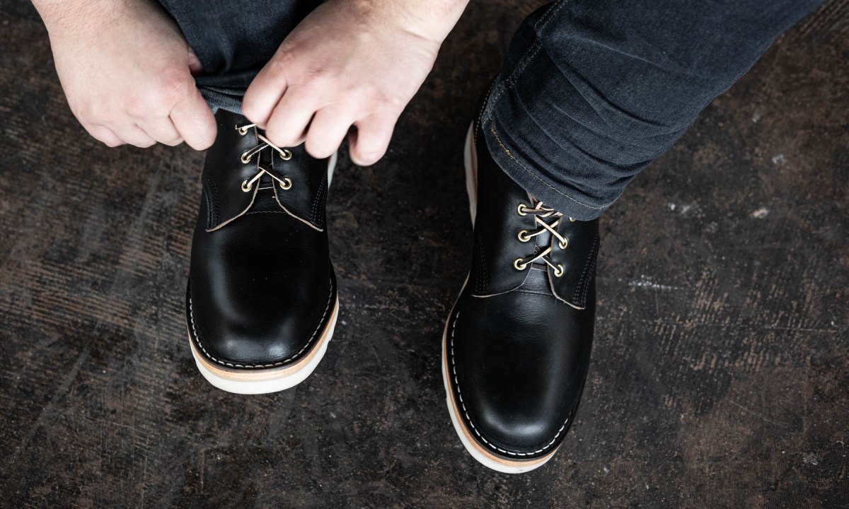 man tying black chukka boot