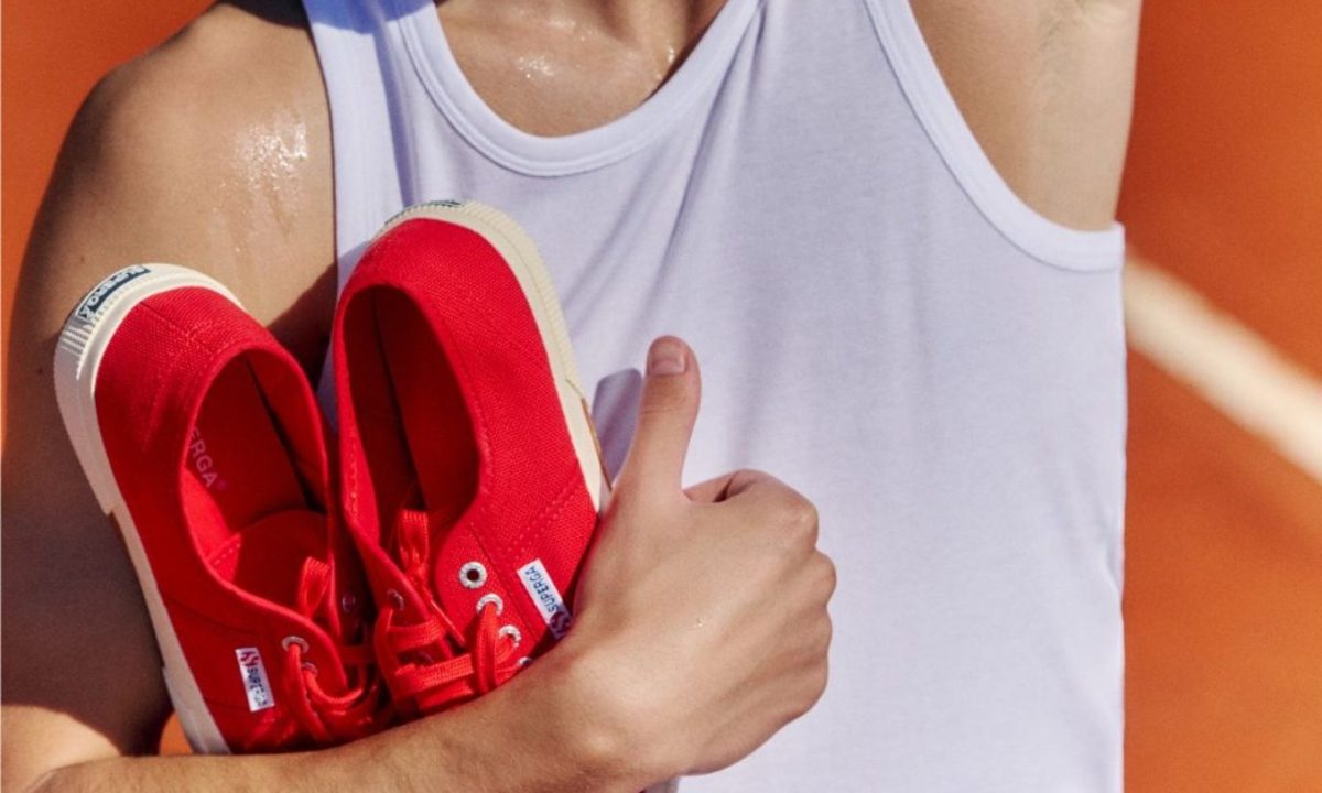 man holding superga sneakers