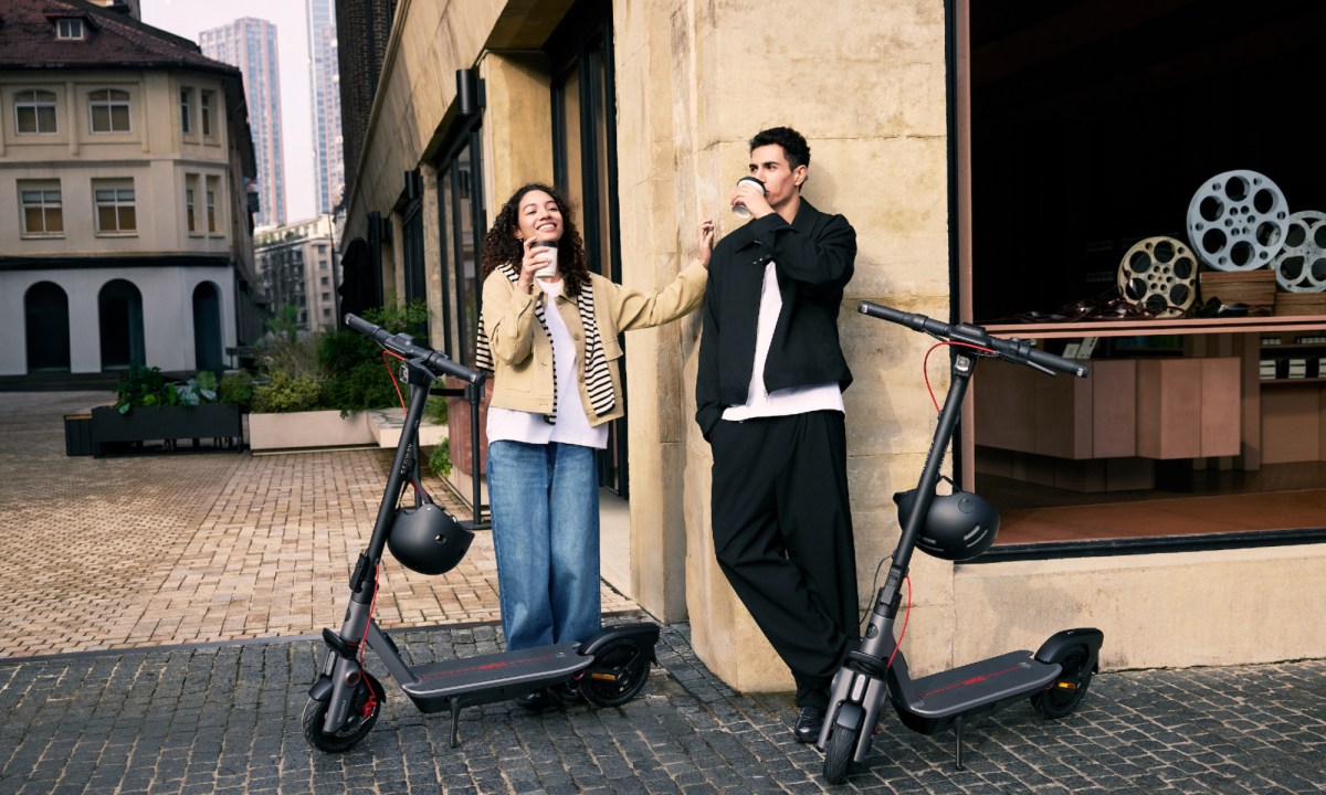 Two people drinking coffee standing by Segway Ninebot F3 eKickScooters.