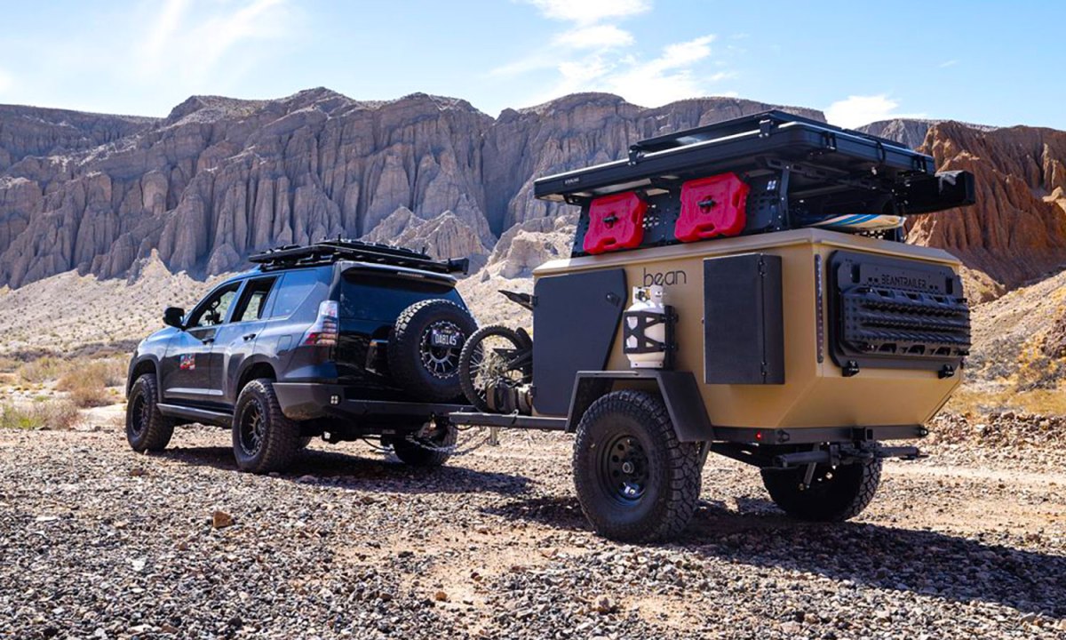 A Toyota SUV towing a Bean Pod adventure travel trailer through the desert.