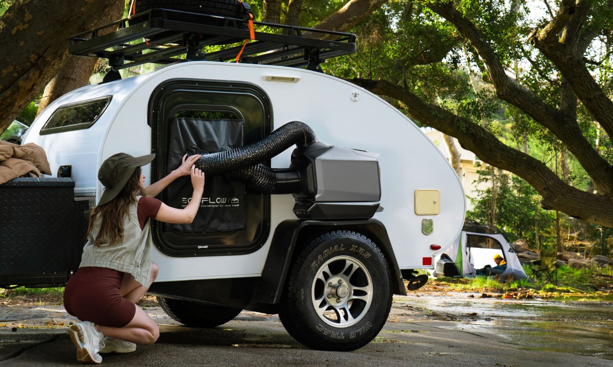 Woman setting up an EcoFlow Wave 3 portable AC/heater outside a towable travel trailer.
