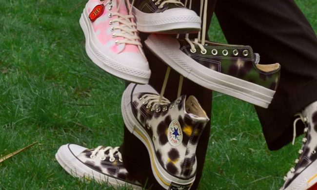 man holding laces of three sneakers