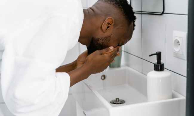 Man in a bathrobe washing his face