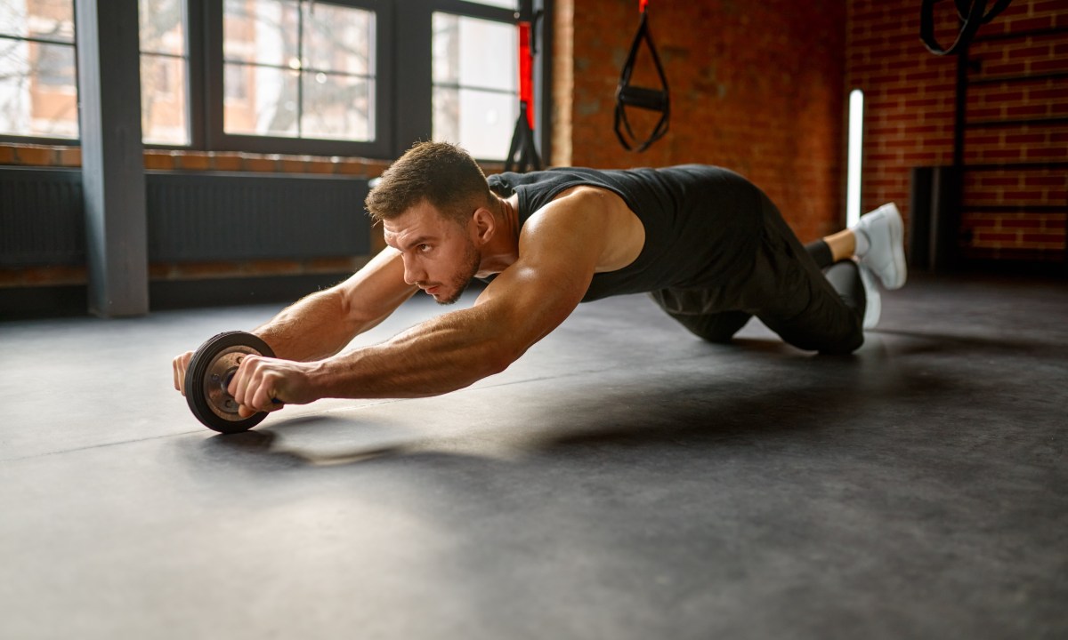 Man training with bare torso abs wheel