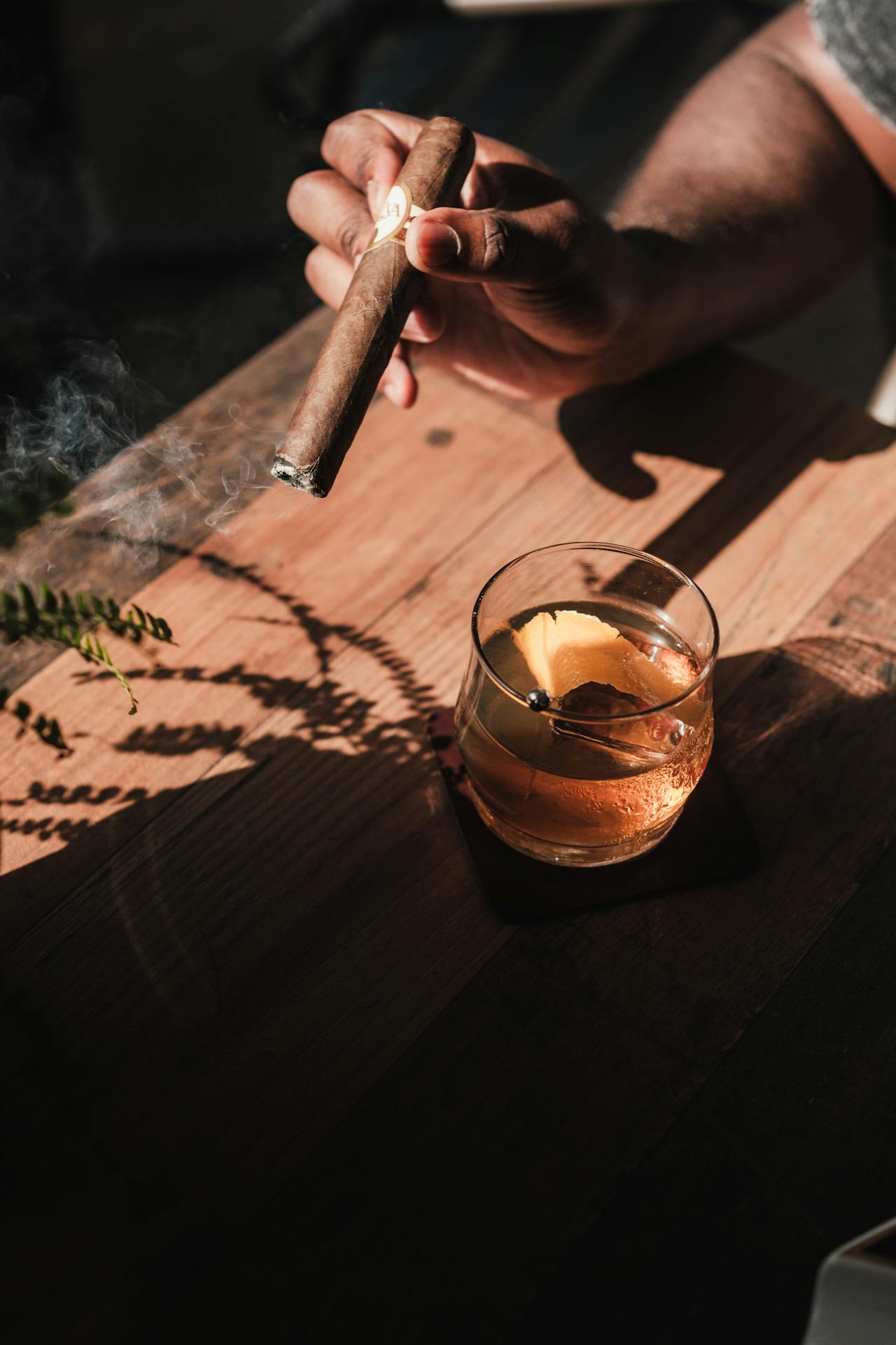 Person holding cigar near liquor