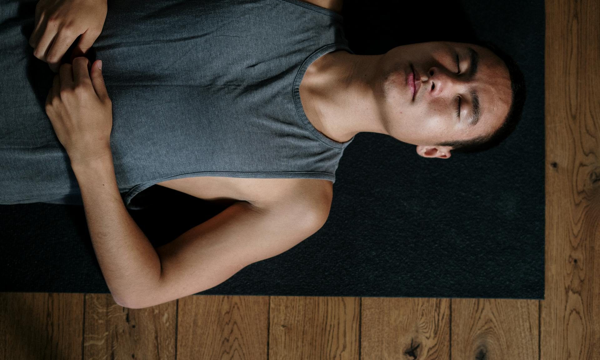 Man laying down on yoga mat on floor peaceful meditation