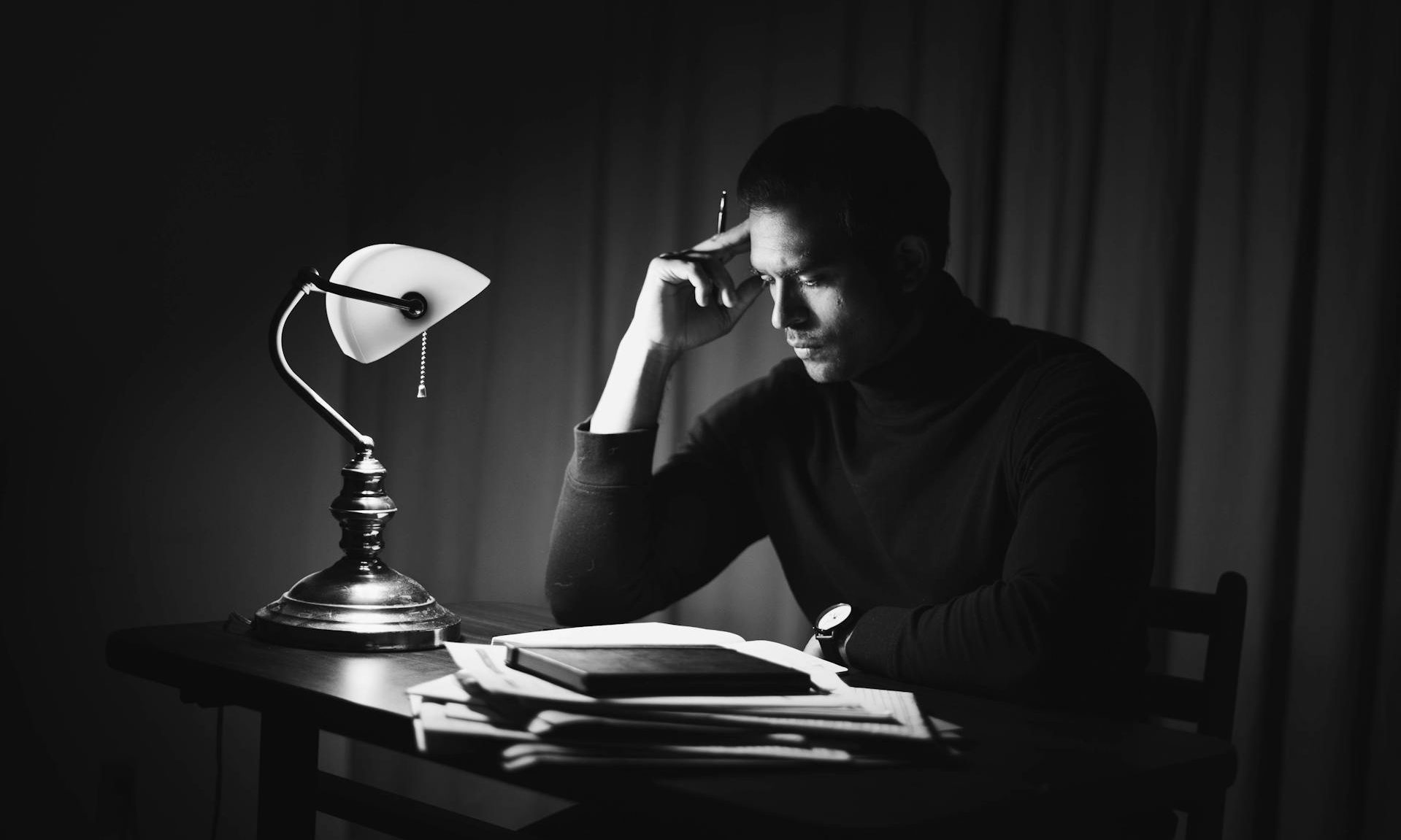 dark picture of man at desk working thinking reading