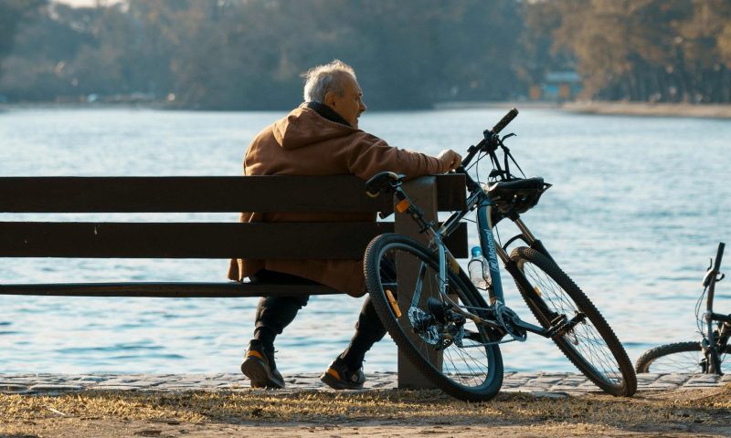 man sitting by his bicycle on bench outside