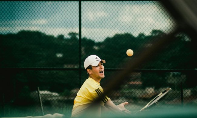 Man swinging tennis racket playing tennis happy