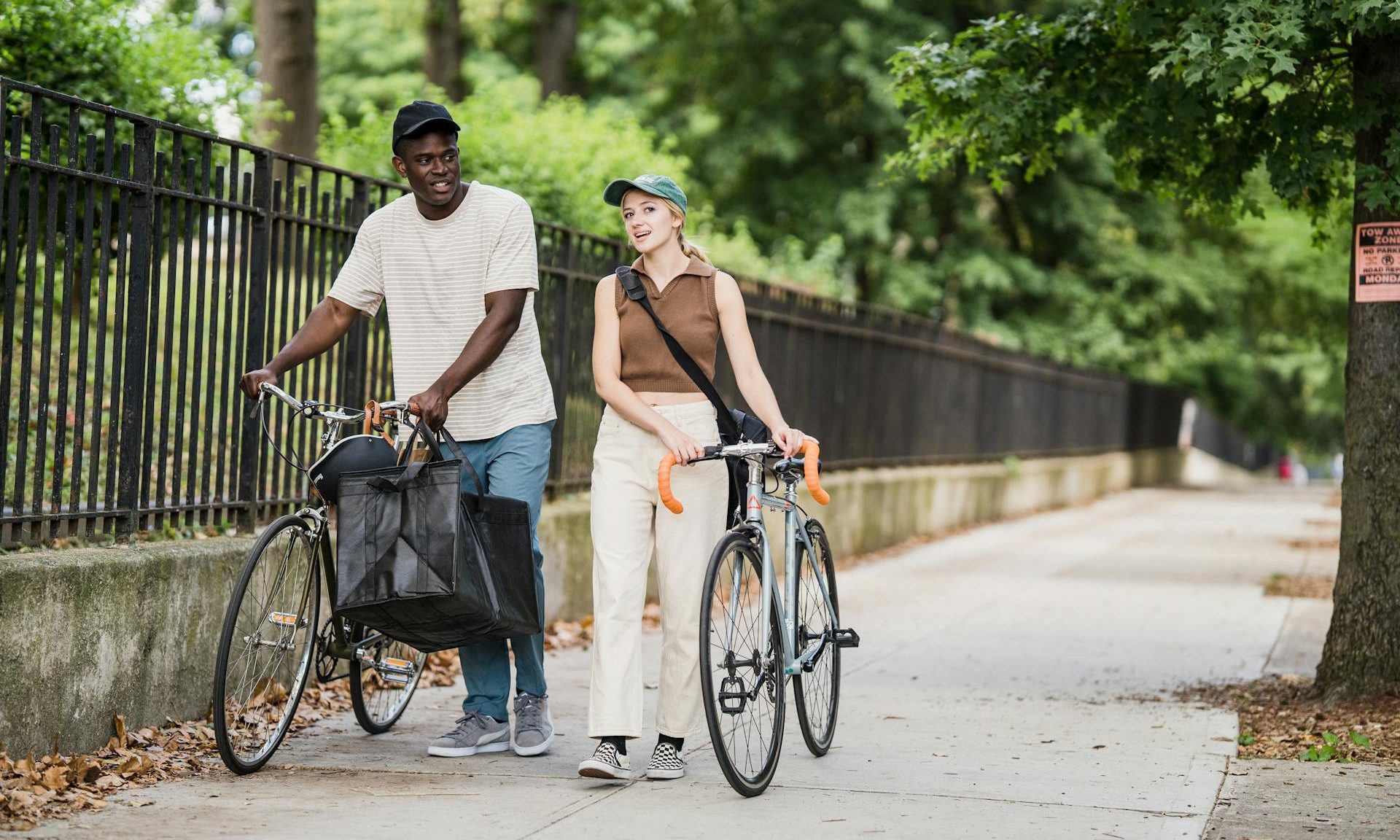 man and woman walking with bicycles bikes outdoors