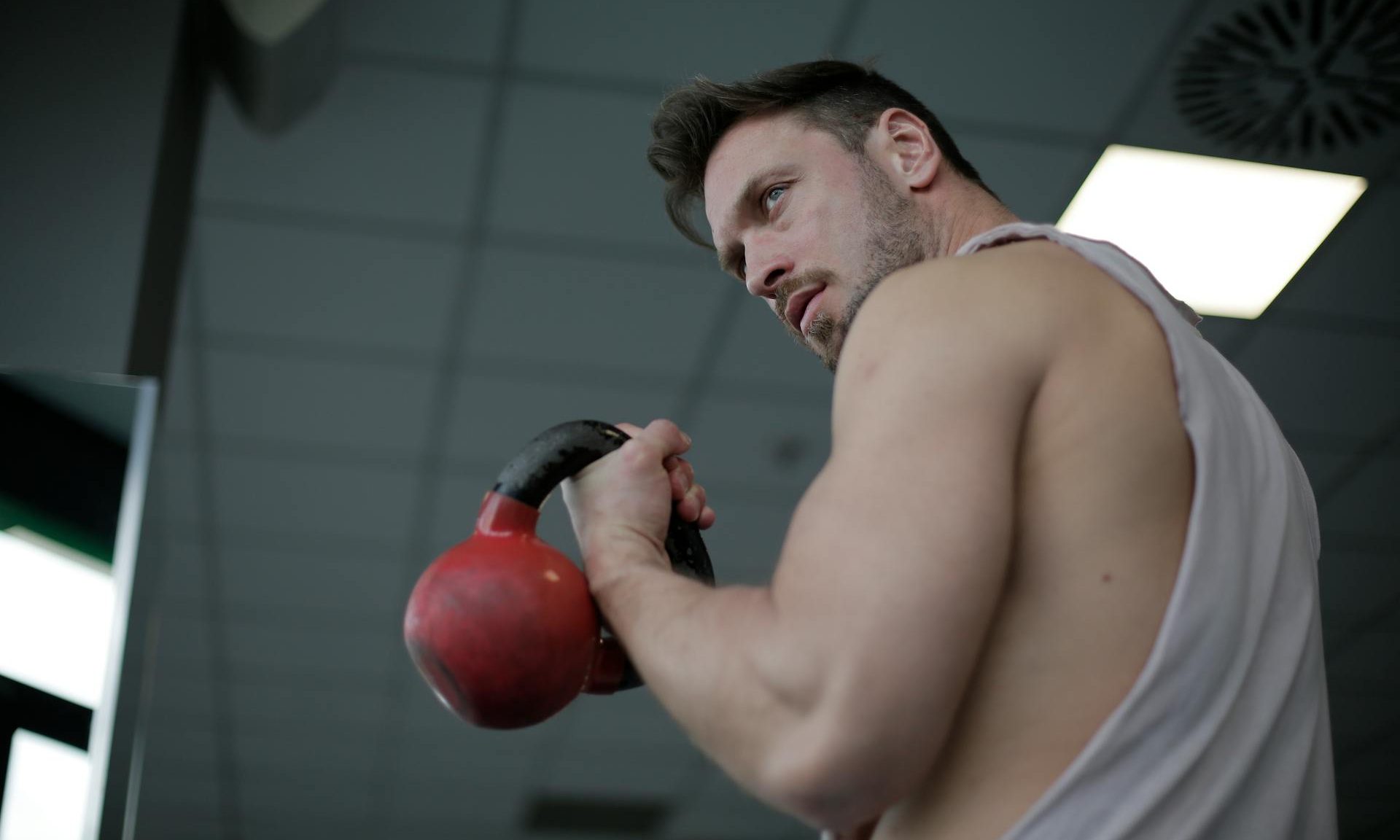 Man lifting kettlebell bicep curl in gym