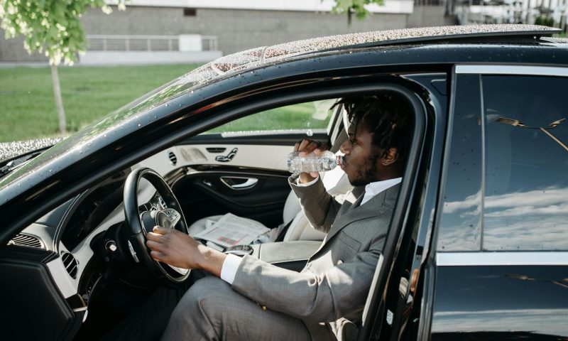 Busy businessman drinking water sitting in car