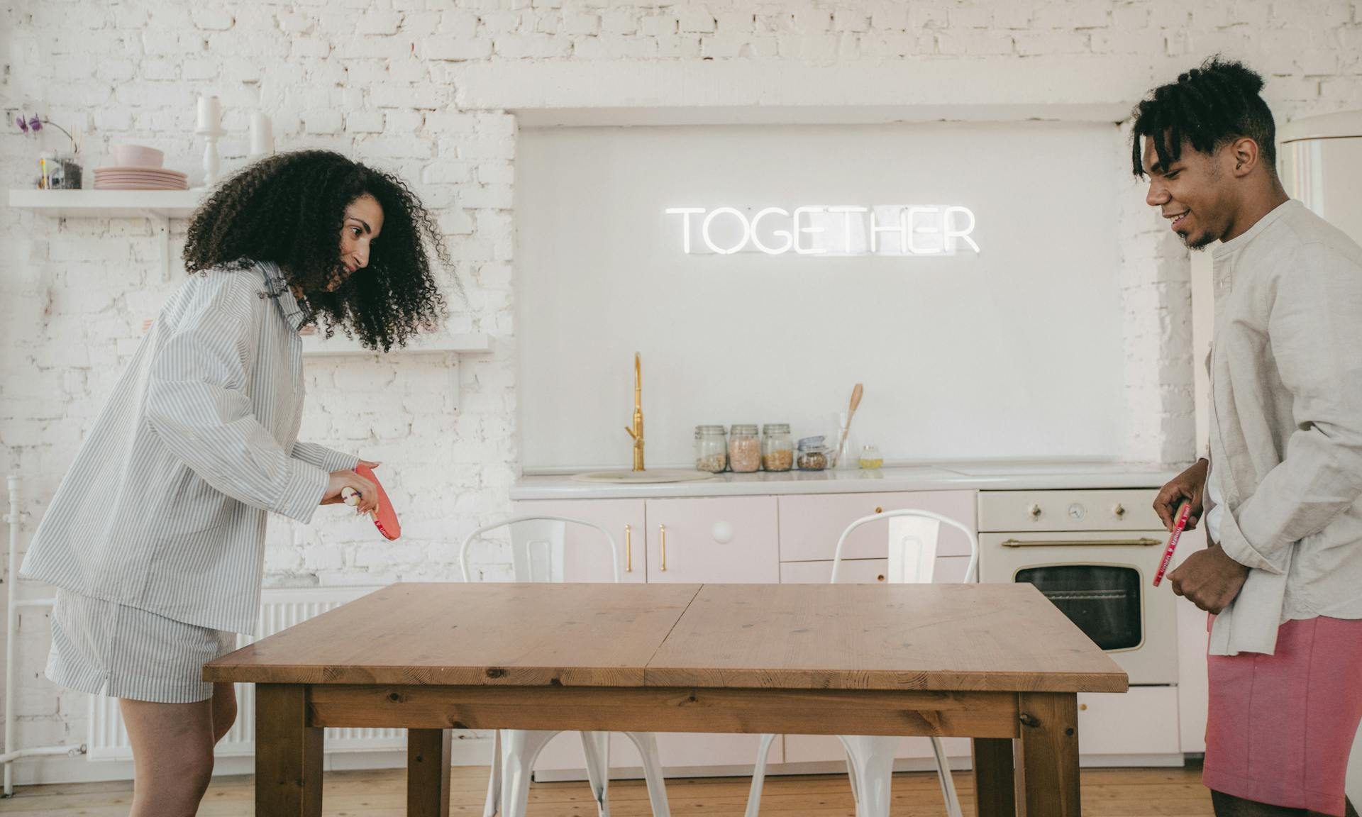 happy man and woman playing table tennis on wooden table