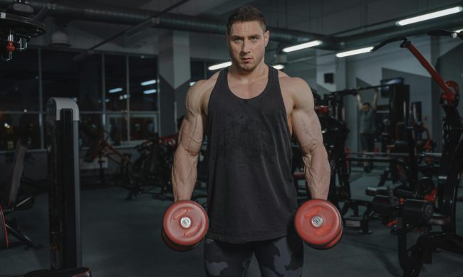 man holding two dumbells in gym