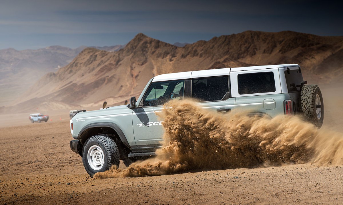 A gray Ford Bronco kicking up sand in the desert with Pirelli Scorpion XTM tires.