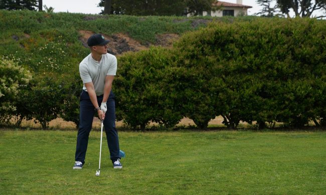 Man holding a golf club about to hit a ball