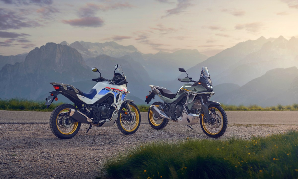 Two 2025 Honda XL750 Transalp motorcycles parked on gravel with mountains in the background.