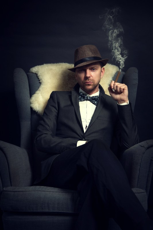 well-dressed gentleman smoking a cigar on an armchair