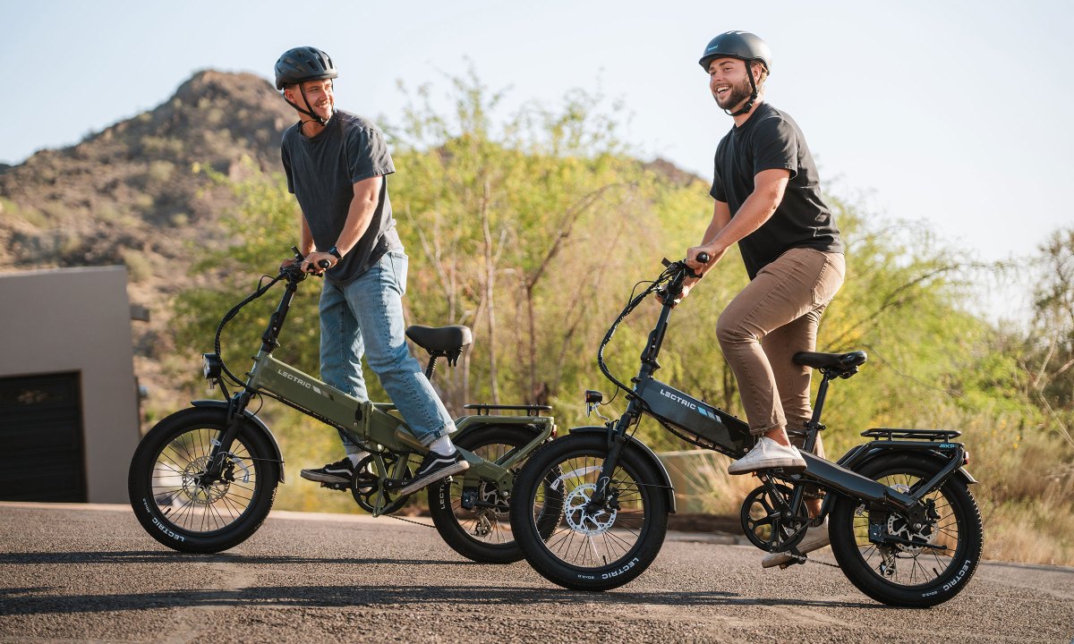A pair of young men riding Lectric's XP4 folding ebike on a neighborhood street.