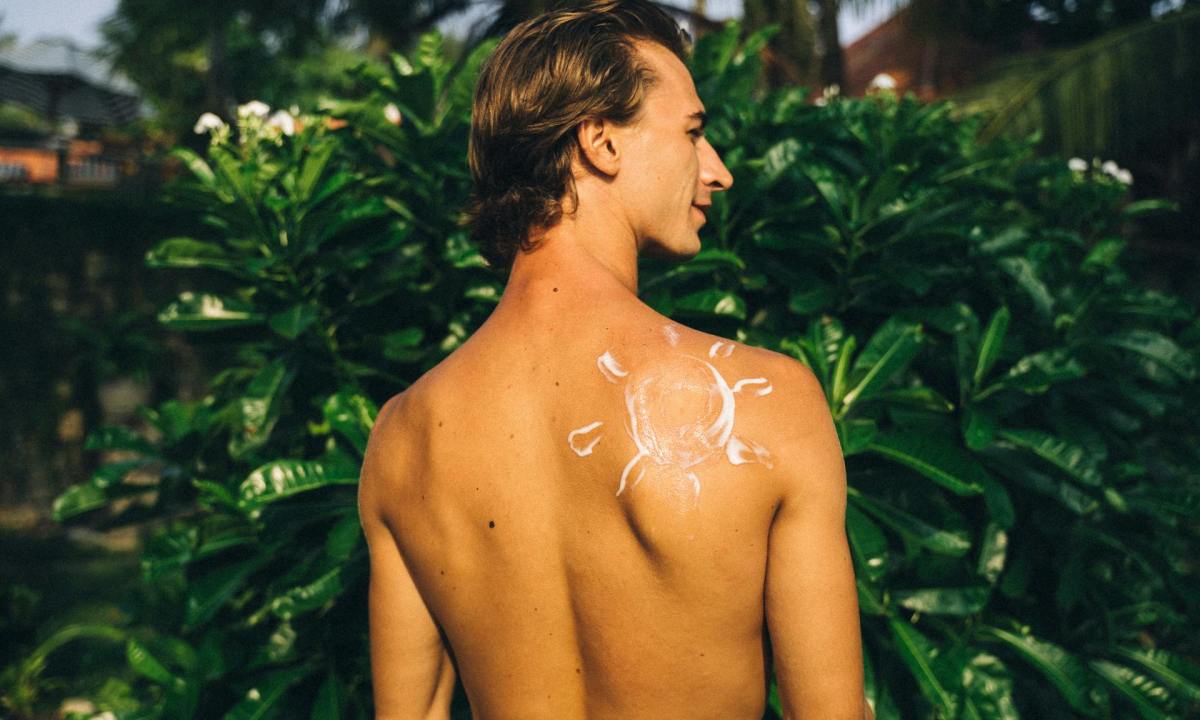 shirtless man with sunscreen on back in shape of sun