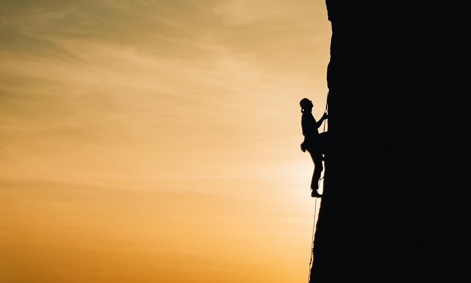 man rock climbing sunset