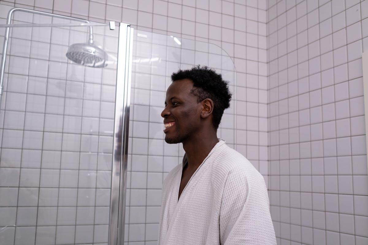 man in shower in white robe