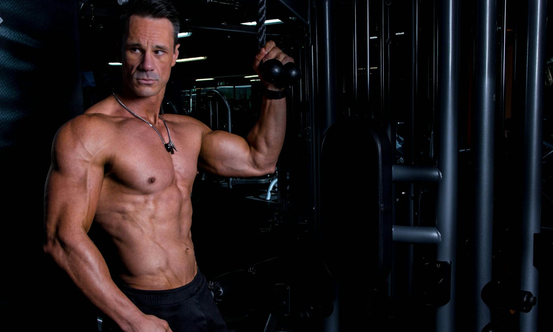 muscular muscle man in gym holding weight machine resistance training weightlifting