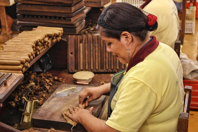 woman hand-rolling a cigar in a factory