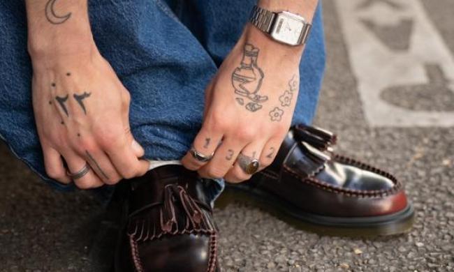 man tying cherry red loafers