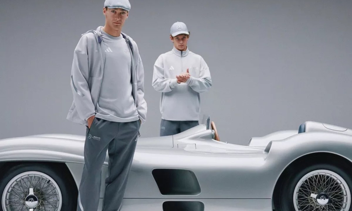 F1 drivers George Russell and Kimi Antonelli wearing Mercedes fan wear with a Mercedes-Benz W196 racecar.