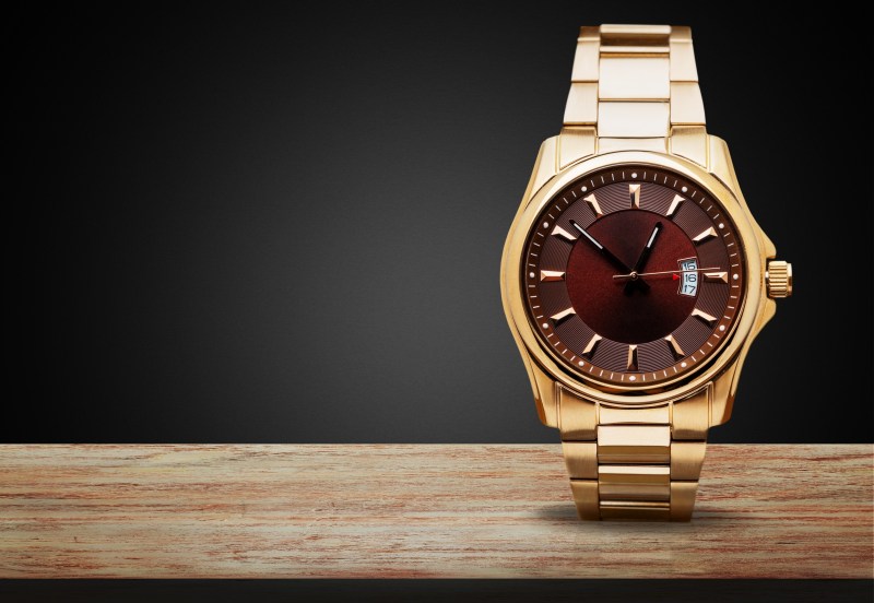 gold watch on wood with black background
