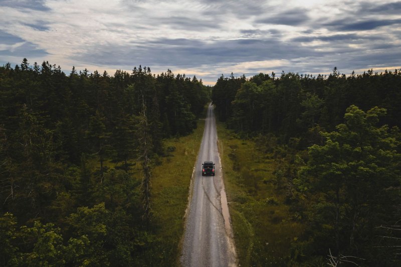 Aerial of an overlanding truck driving a long, straight dirt road.