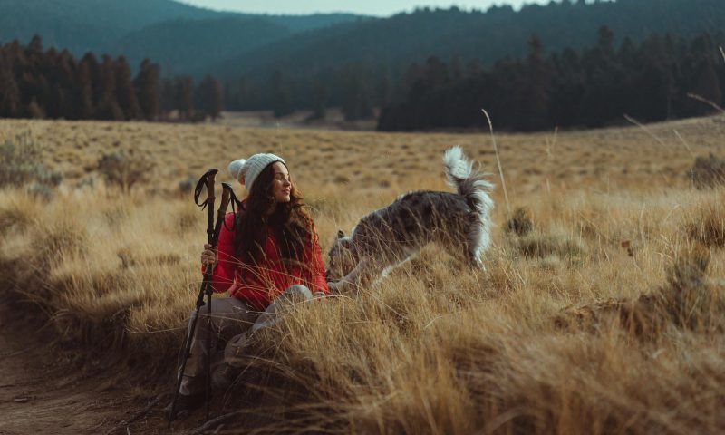 woman and dog sitting down hiking poles