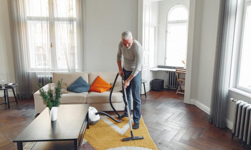 older man vacuuming floor