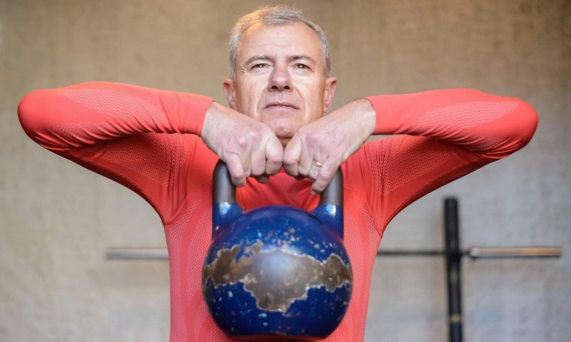 older man holding a kettlebel