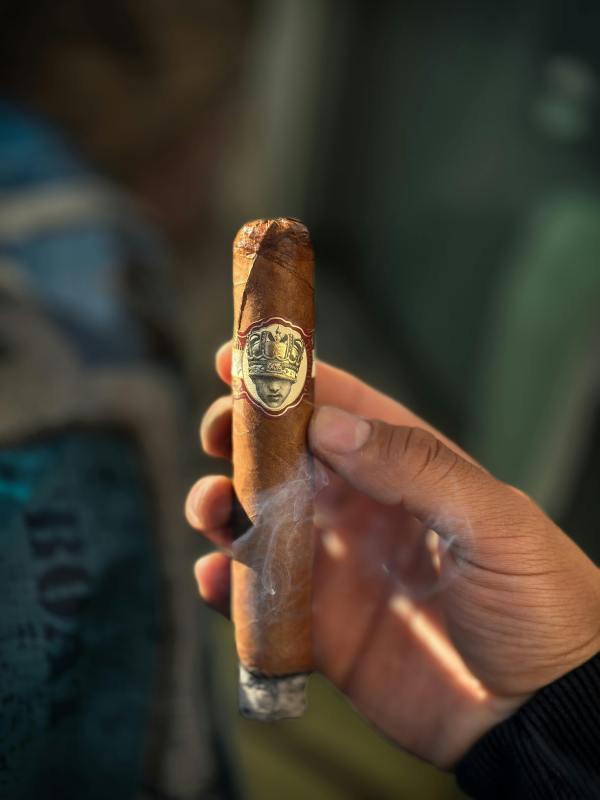 close-up of hand holding a smoking cigar
