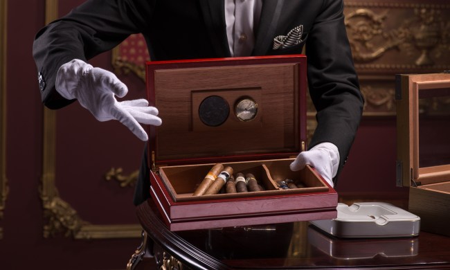 faceless man presenting a cigar humidor with cigars inside with gloved hands