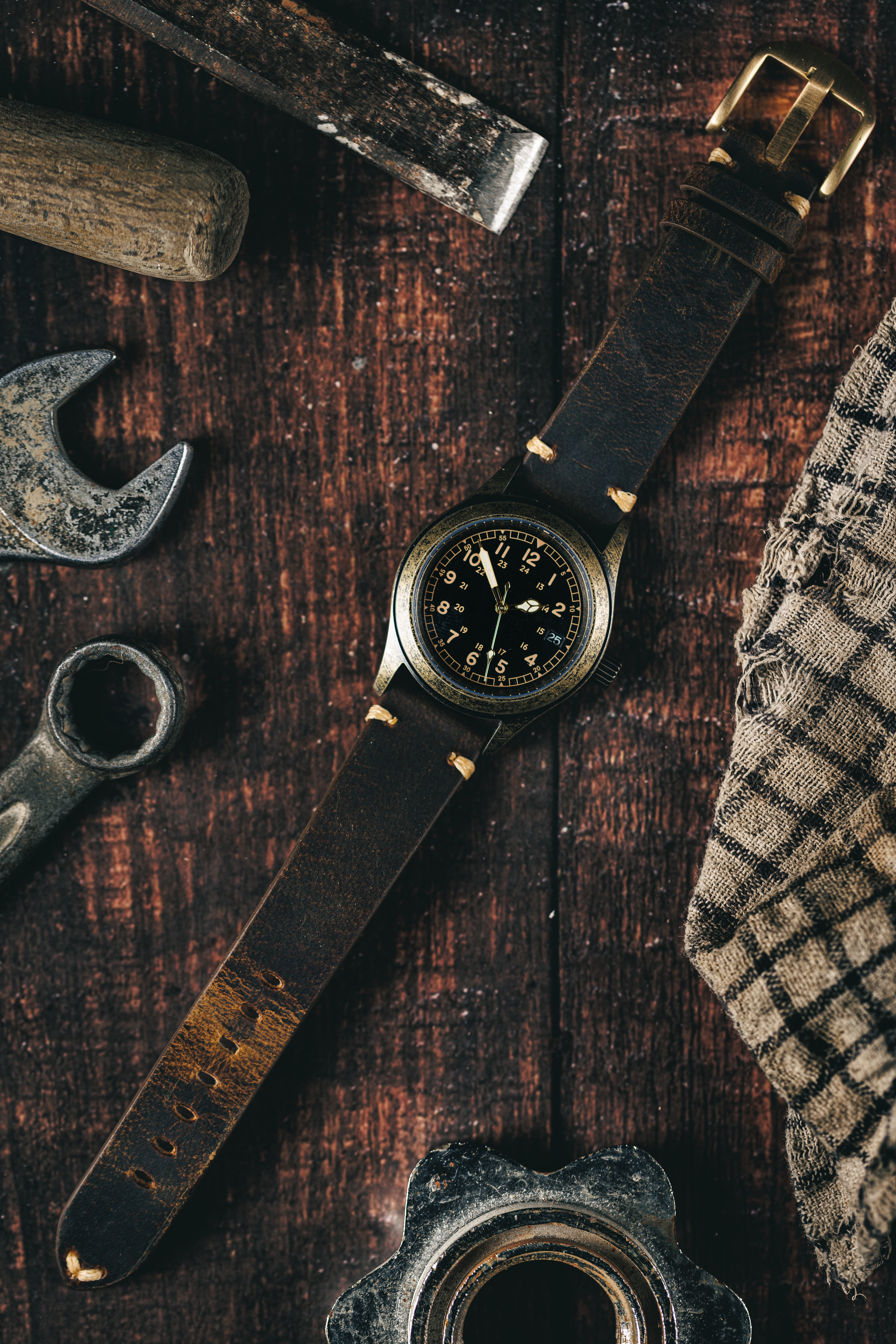 Rustic military-inspired wristwatch on a wooden surface with vintage tools and cloth, capturing an old-world charm and rugged masculinity.