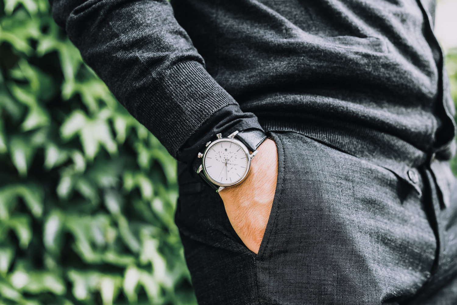 closeup fashion image of luxury watch on wrist of man.body detail of a business man.Man's hand in a grey shirt with cuffinks in a pants pocket closeup. 
