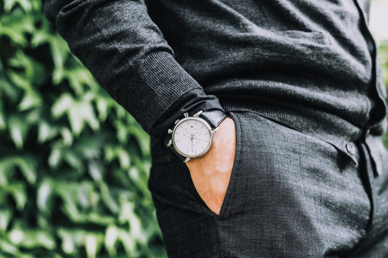 closeup fashion image of luxury watch on wrist of man.body detail of a business man.Man's hand in a grey shirt with cuffinks in a pants pocket closeup.