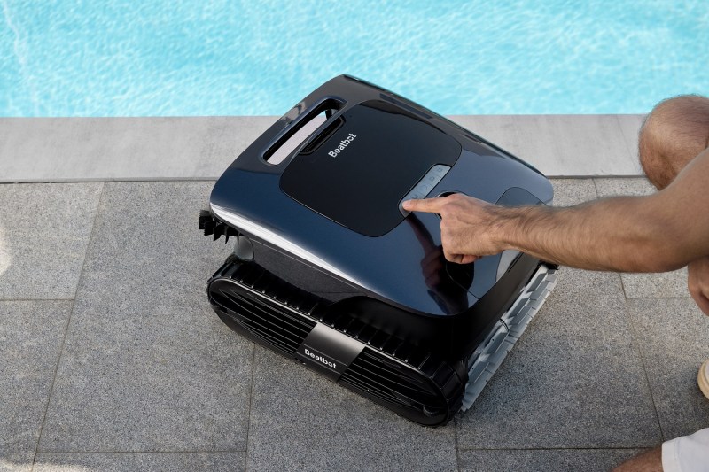 A person pressing a button on the Beatbot AquaSense 2 Ultra robotic pool cleaner.