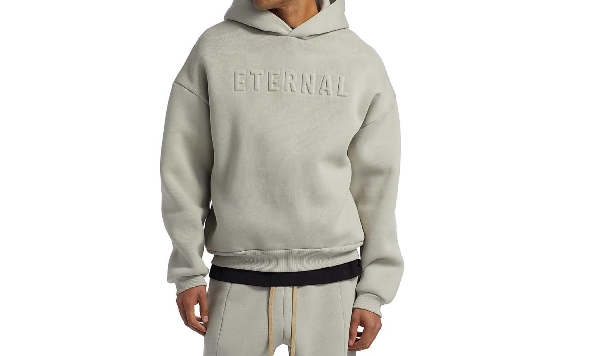 A model wearing the Fear of God Eternal pullover hoodie in dove grey.