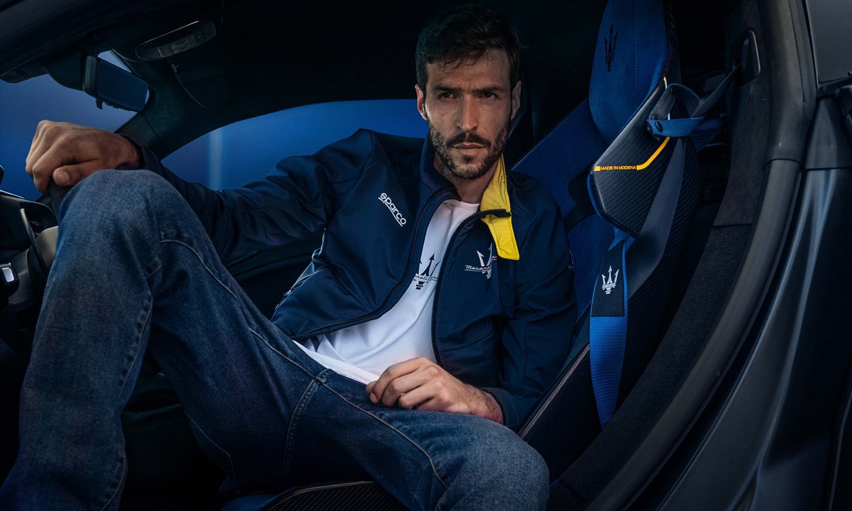 Model sitting in a car wearing clothes from the Sparco X Maserati fan collection.